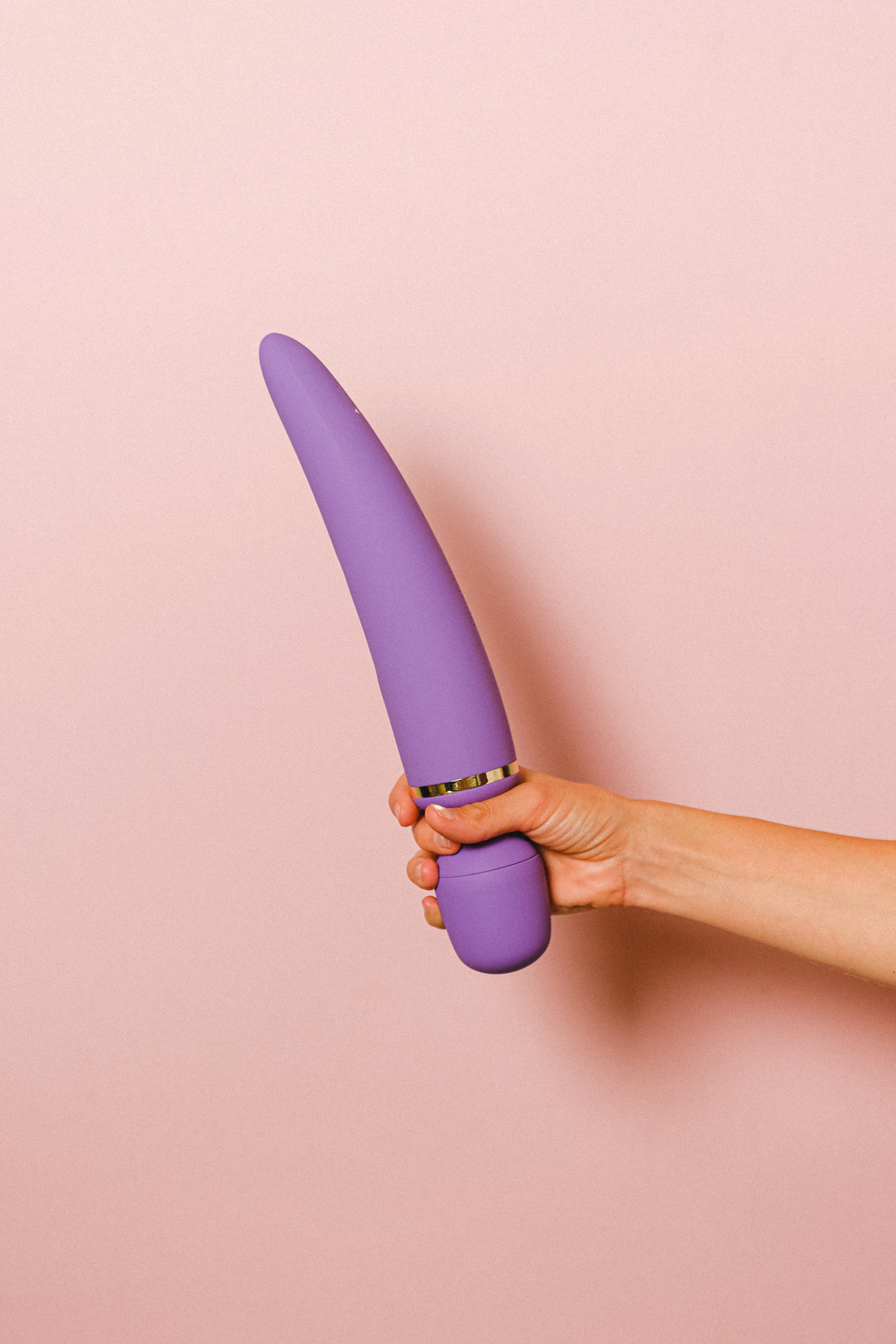 Ein lila Vibrator wird gehalten, Der Vibrator