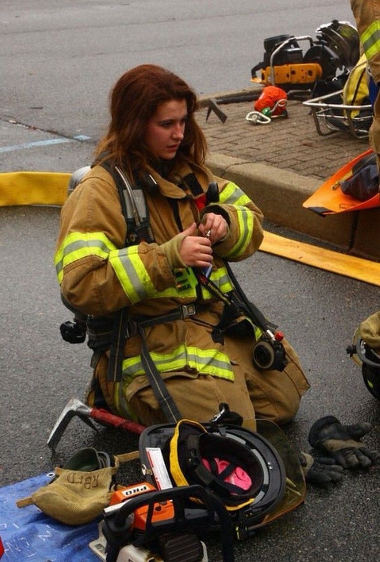 Die Feuerwehrfrau, Eine Feuerwehrfrau kniet auf der Straße